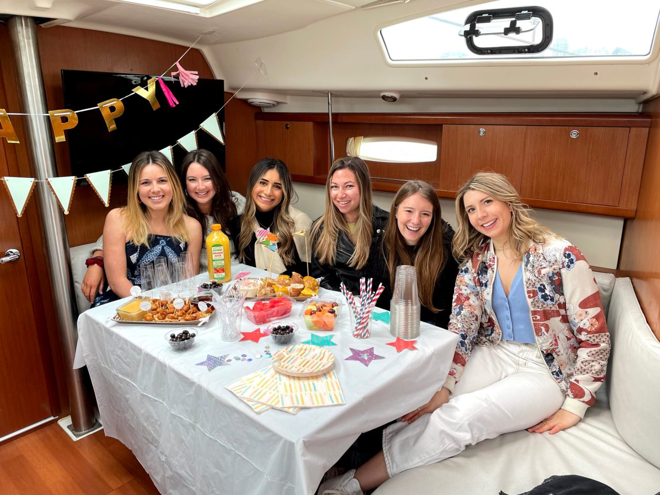 friends sitting a table on a boat with birthday decorations